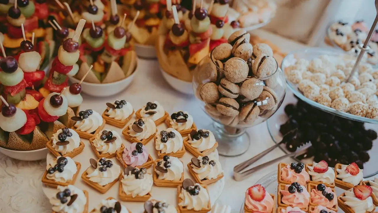 Délicieux assortiment de douceurs pour un brunch mariage : brochettes de fruits, mini gaufres à la crème, macarons et autres gourmandises.