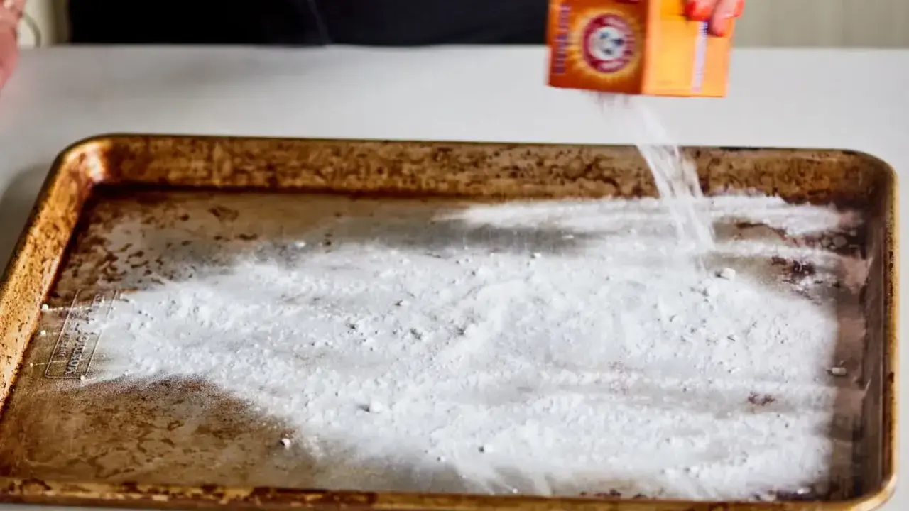 Saupoudrer du bicarbonate de soude sur une plaque de four brûlée. Une astuce pour savoir comment enlever du brûlé sur une plaque de four.