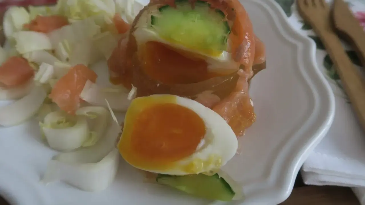 Un œuf en gelée au saumon, garni de concombre et servi avec des dés de saumon fumé et des endives. Un délice !