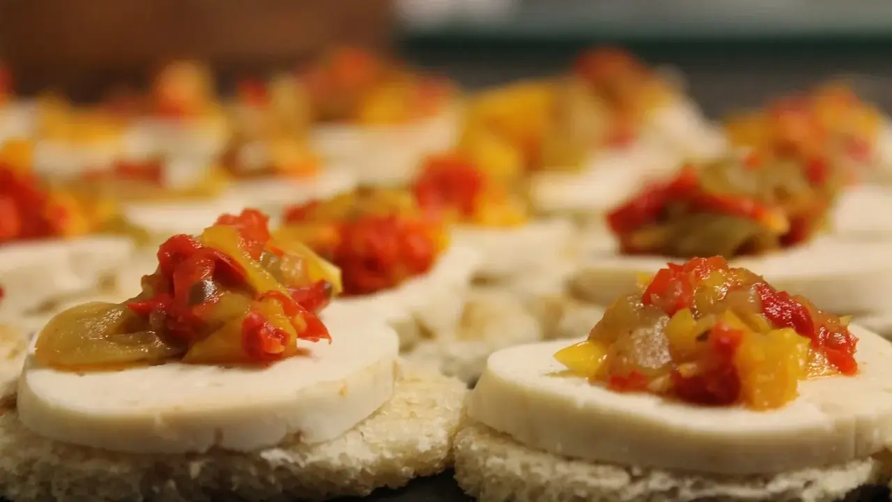 Petits toasts pour l'apéro, garnis de fromage blanc et d'une préparation colorée de poivrons et oignons.