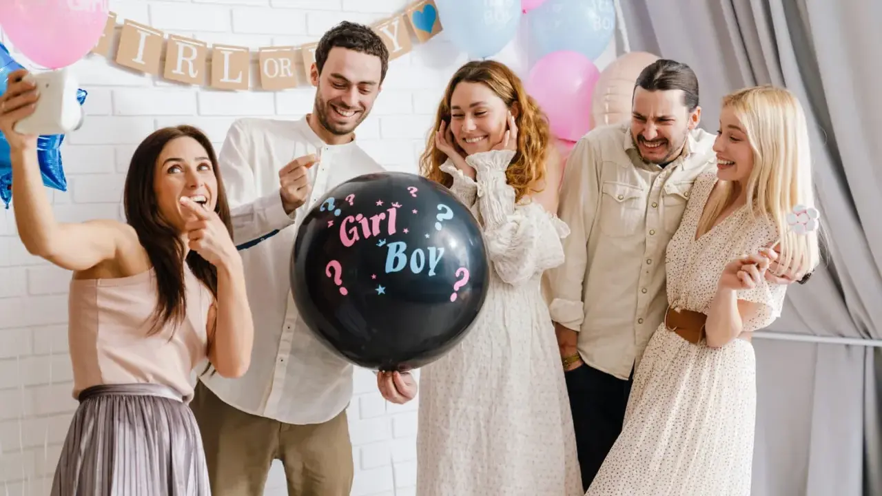 Groupe d'amis joyeux lors d'une annonce sexe du bébé. Un ballon noir avec "Girl? Boy?" au centre de la scène.