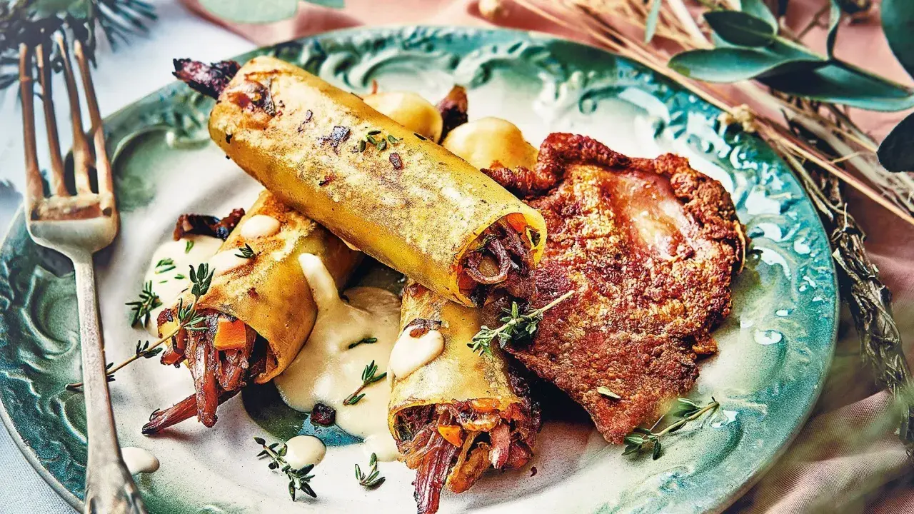 Un délicieux repas d'anniversaire léger : cannellonis farcis à la viande et légumes, accompagnés d'une sauce crémeuse et d'une tranche de viande croustillante.