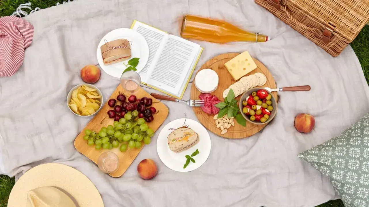 Un plateau de fromages, fruits, sandwichs et chips : voilà quoi prendre pour un picnic parfait.