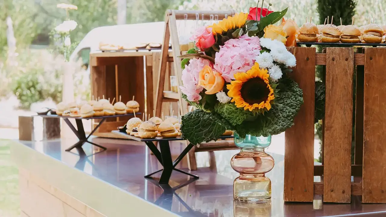 Un buffet de mini-burgers et un bouquet coloré, une belle idée apéro mariage en plein air.