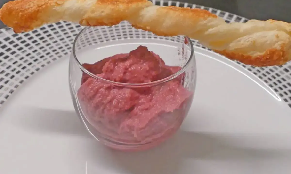 Un verre de houmous de betterave, garni d'un bâtonnet de pâte feuilletée croustillant. Une touche colorée et savoureuse pour l'apéritif.