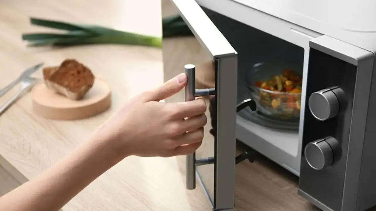 Main tenant ouvre son micro-ondes pour y placer un plat. La question est : peut-on mettre de l'inox au micro-onde ?