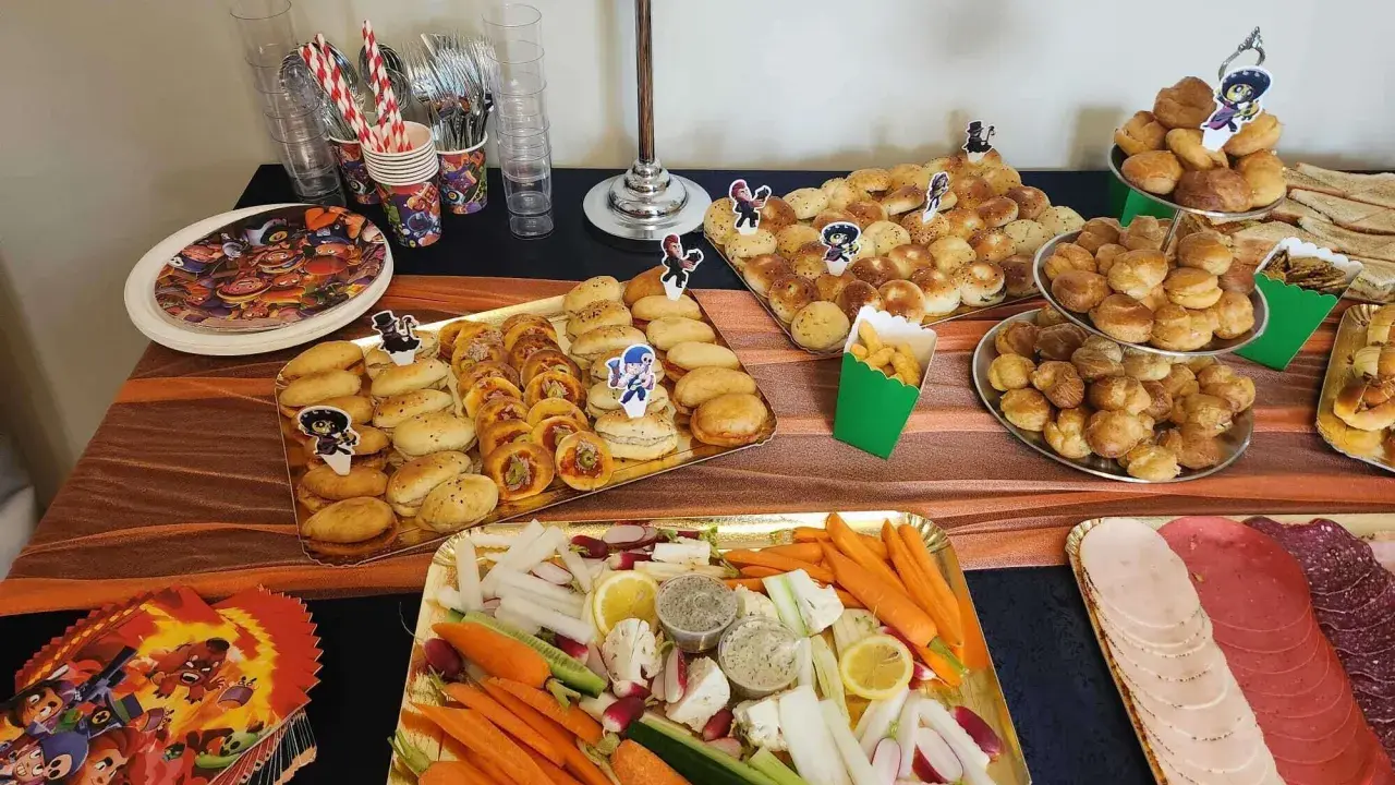Un délicieux buffet froid avec des petits pains, des crudités, des dips et de la charcuterie, parfait pour une fête d'enfants.