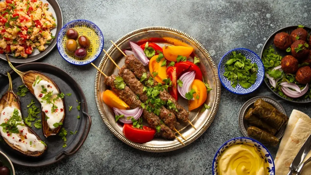 Un festin de plat méditerranéen : brochettes de viande, aubergines rôties, falafels, feuilles de vigne farcies, houmous et salade de couscous.