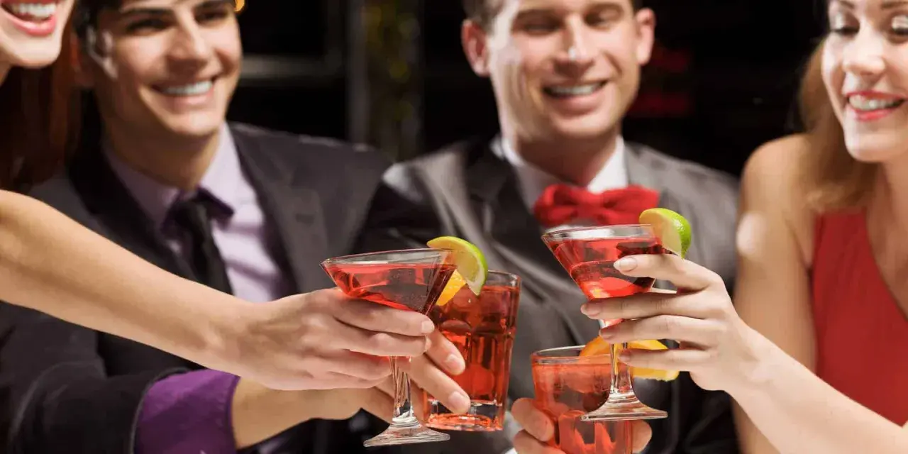 Des amis célèbrent avec des cocktails rouges, des rondelles de citron vert et d'orange. Une soirée de jeux du goût et de bonne humeur.