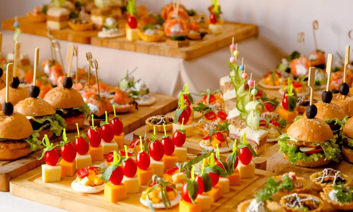 Buffet de petits fours variés : mini-burgers, toasts au saumon, brochettes de tomates et dés de fromage. Une belle idée pour une recette petit four réussie.