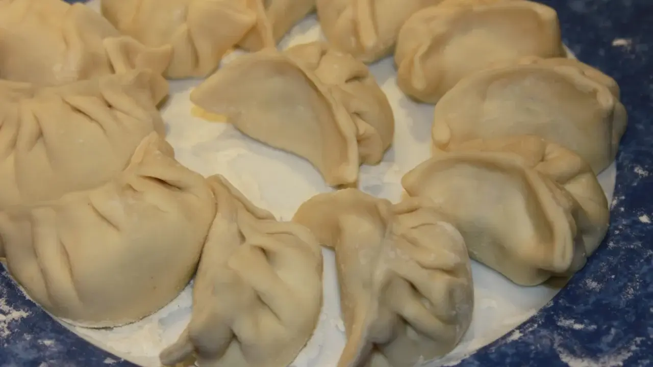 Assiette de ravioli pekinois crus, prêts à être cuisinés. La pâte est fine et plissée, prête à accueillir une garniture savoureuse.