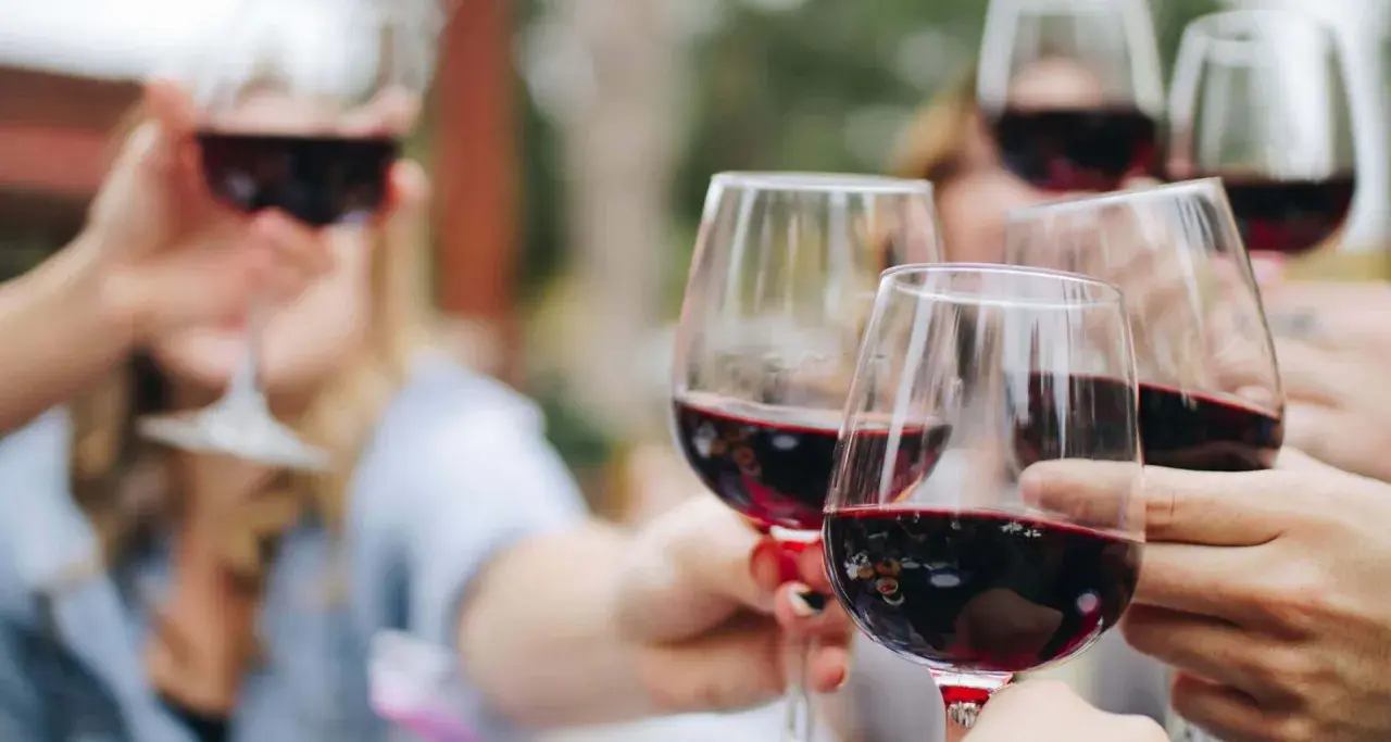Des verres de vin rouge levés en toast. Pour 40 personnes, combien de bouteille de vin prévoir ? Environ 15 à 20 bouteilles.