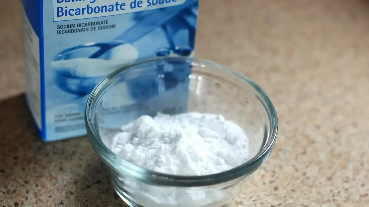 Un bol de bicarbonate de soude à côté de sa boîte. Un ingrédient polyvalent, utile pour le nettoyage et la cuisine, et même pour des expériences scientifiques impliquant de l'aluminium.