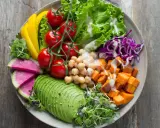 Un bol coloré avec avocat, tomates, pois chiches, patates douces, chou rouge, radis et poivron jaune. Parfaites salades originales pour buffet.