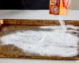 Saupoudrer du bicarbonate de soude sur une plaque de four brûlée. Une astuce pour savoir comment enlever du brûlé sur une plaque de four.