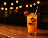 Un verre de punch sans alcool, garni de fruits frais et d'une paille, sur un bar en bois, avec des lumières douces en arrière-plan.