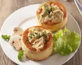 Deux bouchées à la reine maison, garnies d'une sauce crémeuse aux champignons et persil, servies avec des champignons frais et une feuille de laitue.