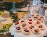 Un buffet de mariage avec des tartellettes aux fruits rouges, du fromage et des raisins. Une belle idée buffet mariage pour un événement gourmand.