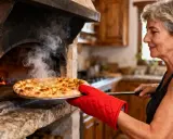 Une femme sort une pizza dorée d'un four à bois. La vapeur s'échappe, promettant un délice à cuire.