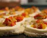 Petits toasts pour l'apéro, garnis de fromage blanc et d'une préparation colorée de poivrons et oignons.