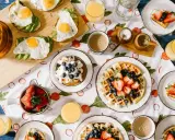 Un petit déjeuner continental ou américain avec des toasts à l'avocat et aux œufs, des gaufres aux fruits rouges et des jus.