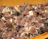 Un plat de fromage de tête, avec des morceaux de viande et de cartilage, dans un récipient en bois.