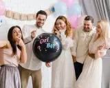 Groupe d'amis joyeux lors d'une annonce sexe du bébé. Un ballon noir avec "Girl? Boy?" au centre de la scène.