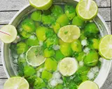 Un grand bol rempli de citrons verts, de menthe et de glaçons, prêt pour une recette mojito sans alcool 5 litres.