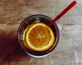 Verre de boisson sans alcool pour accompagner repas, avec rondelles d'orange et glaçons, sur fond de bois.