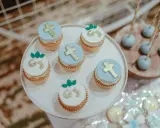 Jolis cupcakes décorés de croix dorées et de lettres pour un buffet dessert baptême. Des cake pops bleus sont aussi présents.