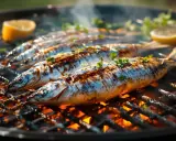 Sardines grillées sur le feu, parsemées de persil et accompagnées de quartiers de citron. Une délicieuse sardinade recette à savourer.