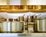 Une cuisine professionnelle avec des casseroles en acier inox 18/10 étincelantes. Des robinets chromés et des gicleurs de sécurité complètent l'ensemble.