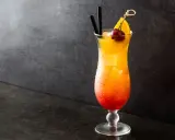 Cocktail Sex on the Beach recette 5l, dégradé rouge-orange, garni d'une cerise et d'une tranche d'orange.