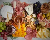 Plateau charcuterie et fromages : un buffet généreux avec jambon, saucisson, fromages variés, fruits, noix et confitures.
