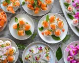 Idée entrée froide mariage : assortiment de sushis et makis raffinés, décorés de saumon, œufs de poisson, herbes fraîches et fleurs comestibles.