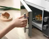 Main tenant ouvre son micro-ondes pour y placer un plat. La question est : peut-on mettre de l'inox au micro-onde ?