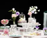 Buffet vin d'honneur fait maison : macarons colorés, meringues, guimauves et fleurs dans des vases.