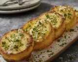 Cinq rondelles dorées de polenta croustillante, saupoudrées de persil frais et de parmesan râpé, sur un plateau.