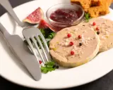 Assiette de foie gras, figues, confiture de fruits rouges et toasts. Une présentation raffinée pour un délice.