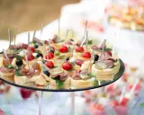 Plateau de petits fours variés, parfaits pour une idée repas baptême. Mini-brochettes avec tomates cerises, olives, charcuterie et fromage sur pain.