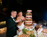 Un couple coupe un dessert mariage original, une tour de gâteaux aux fraises et à la crème, lors d'une réception nocturne.