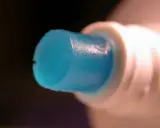 Goutte de dentifrice bleu sortant d'un tube blanc, parfaite pour polir l'aluminium.