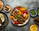 Un festin de plat méditerranéen : brochettes de viande, aubergines rôties, falafels, feuilles de vigne farcies, houmous et salade de couscous.