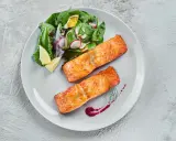Deux pavés de saumon au four, accompagnés d'une salade fraîche et de quartiers de citron. Un délice simple et savoureux.