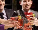 Des amis célèbrent avec des cocktails rouges, des rondelles de citron vert et d'orange. Une soirée de jeux du goût et de bonne humeur.