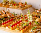 Buffet de petits fours variés : mini-burgers, toasts au saumon, brochettes de tomates et dés de fromage. Une belle idée pour une recette petit four réussie.
