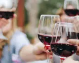 Des verres de vin rouge levés en toast. Pour 40 personnes, combien de bouteille de vin prévoir ? Environ 15 à 20 bouteilles.