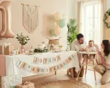 Une famille célèbre la fête découverte bébé avec un gâteau, des ballons et une bannière "Joyeux 1er Anniversaire".