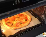 Une pizza dorée cuit dans un four, sa croûte gonflée et son fromage fondant témoignent de la parfaite fonction pizza four.