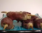 Brochettes de boeuf roulées autour de fromage fondant, servies sur une assiette bleue.
